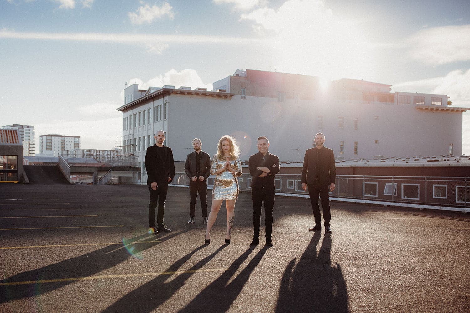 Hands Off band on Auckland rooftop with backlit golden sun flare