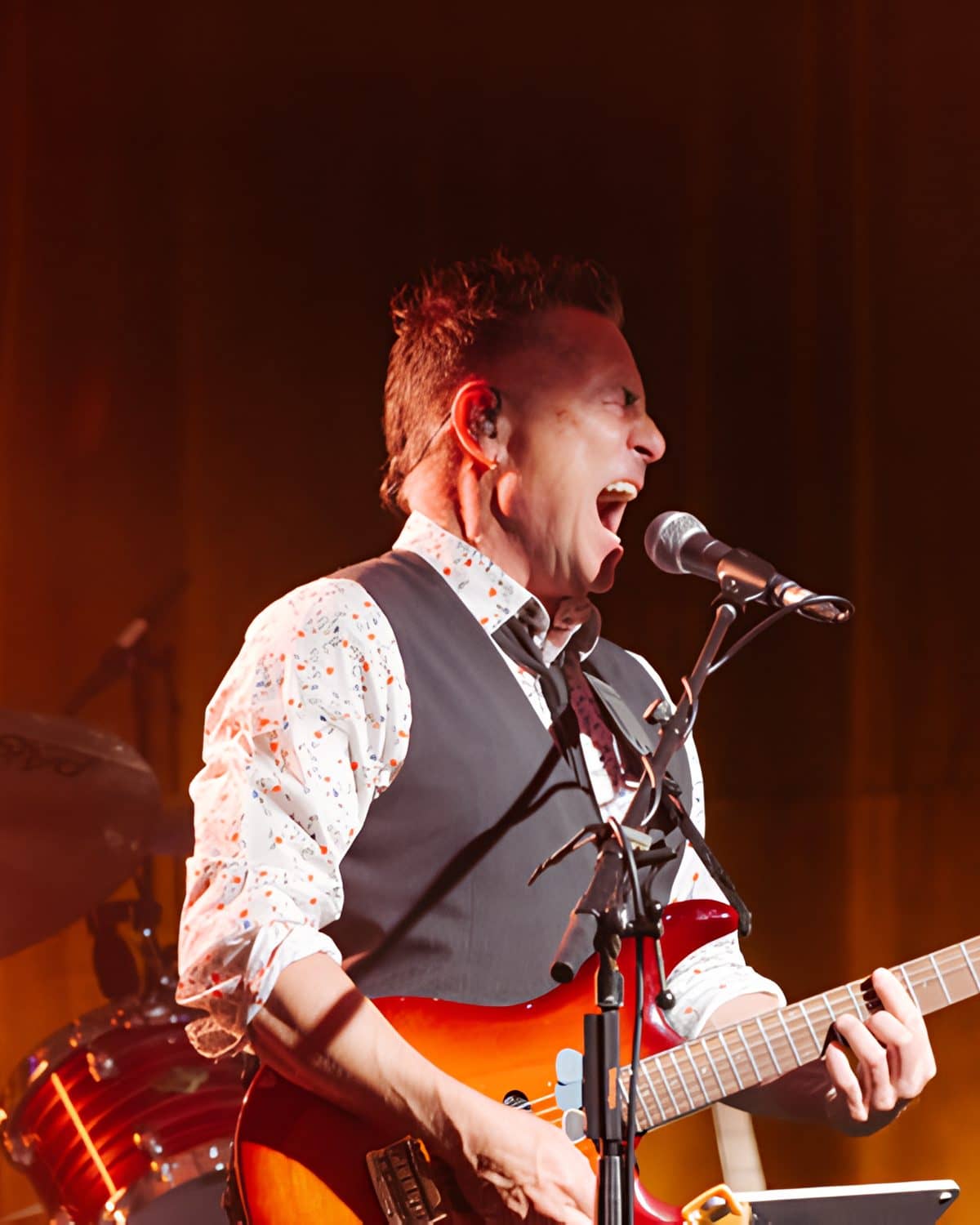 Guitarist singing into the mic under warm stage light