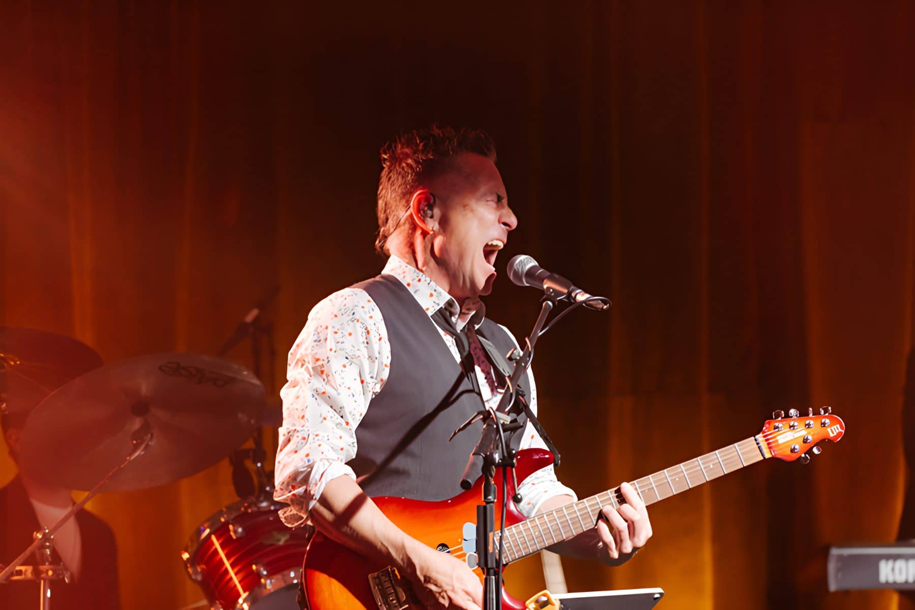Guitarist singing into the mic under warm stage light