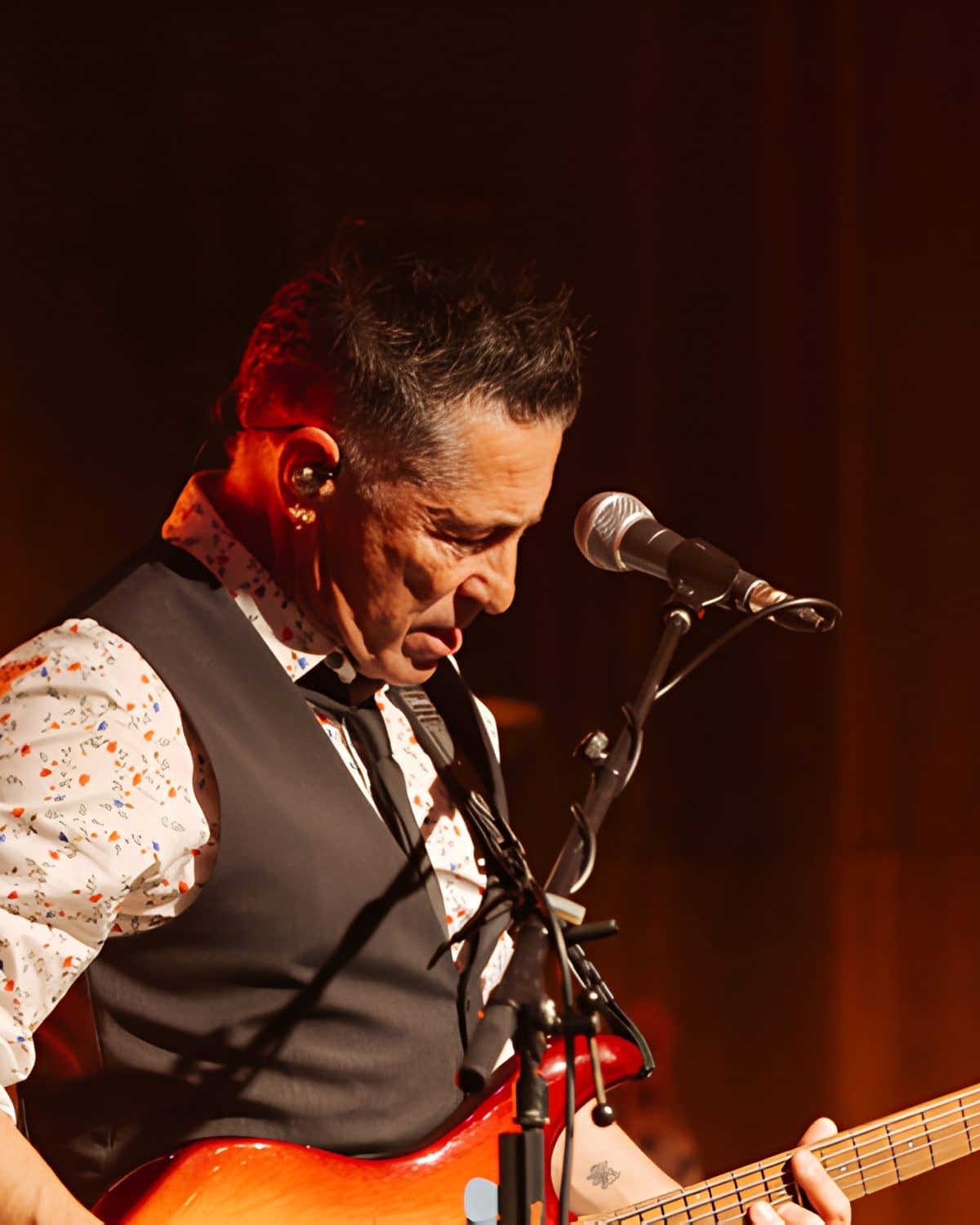 Guitarist head down over a red electric guitar