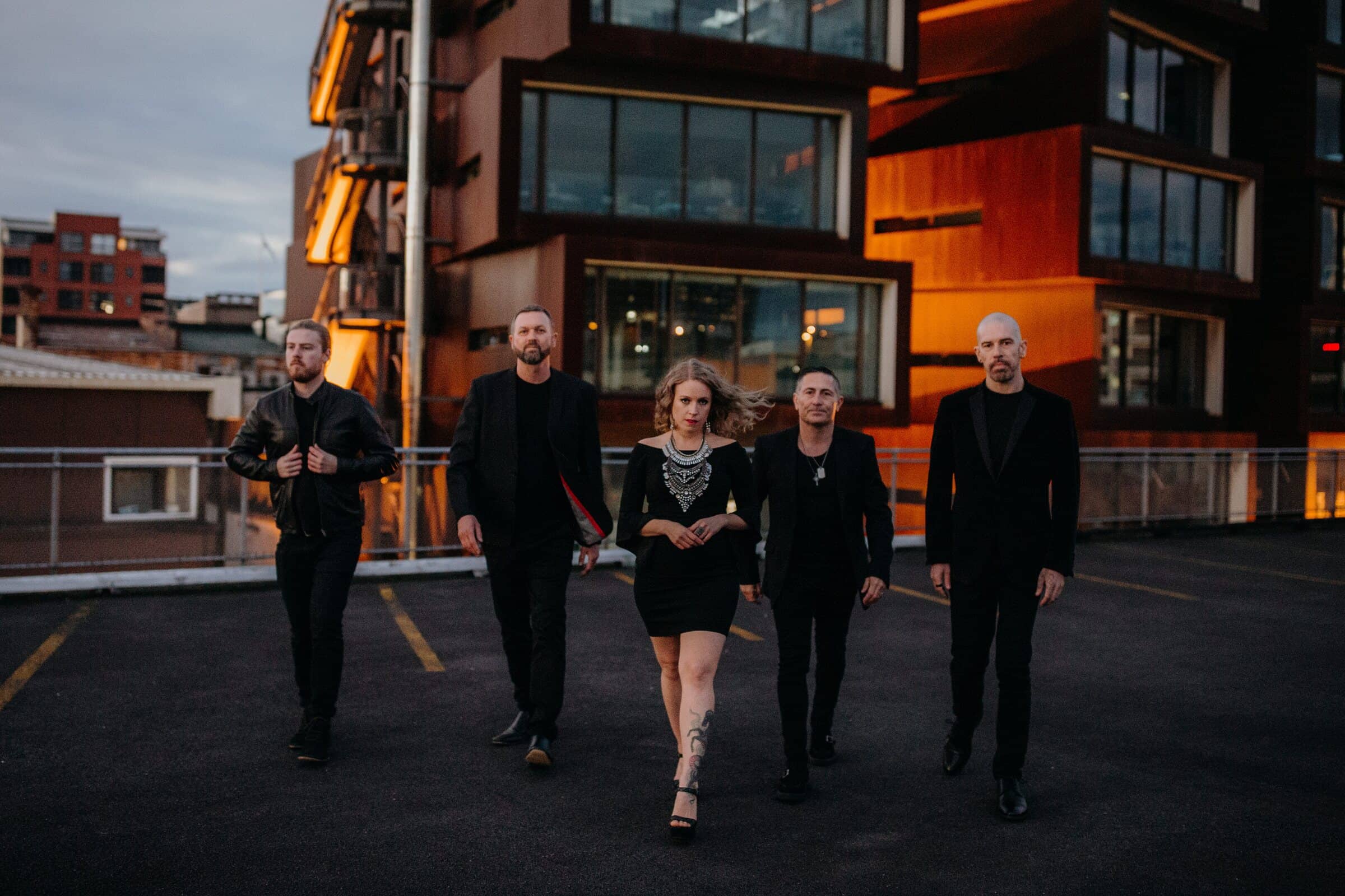 Hands Off, all five members, walking across an Auckland rooftop car park at dusk