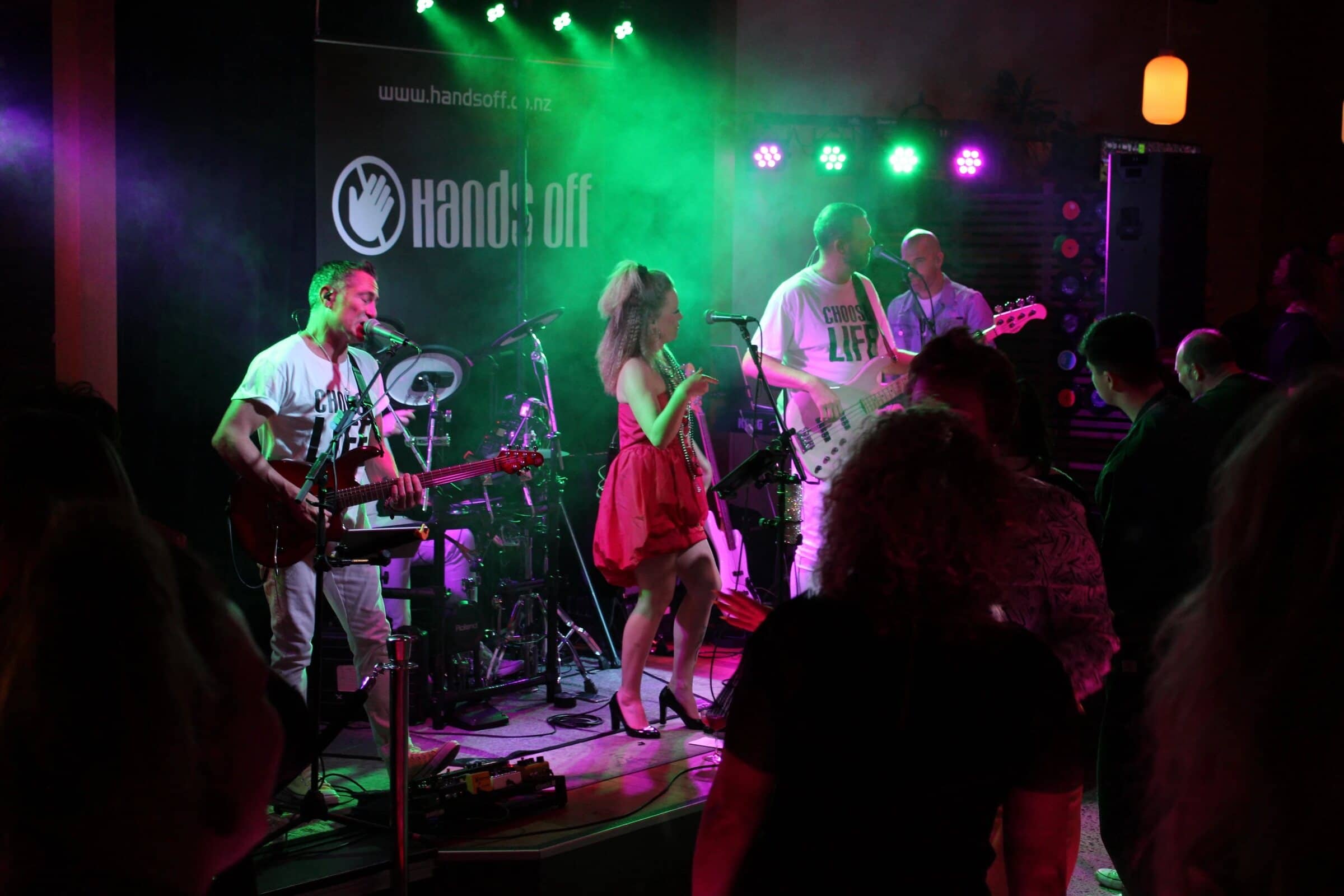 Hands Off on stage under green and pink lights, a crowd dancing in front